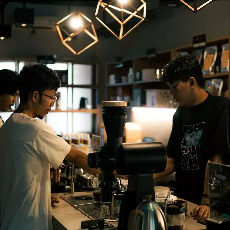 Dua barista meracik kopi menggunakan grinder profesional dengan biji kopi pilihan dari supplier biji kopi pilihan Gemi.