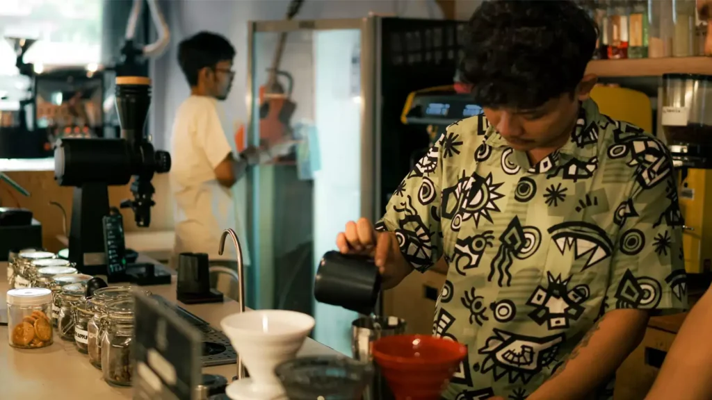 Barista sedang menyajikan kopi dengan biji kopi pilihan, didukung oleh supplier biji kopi pilihan Gemi Coffee Supply.