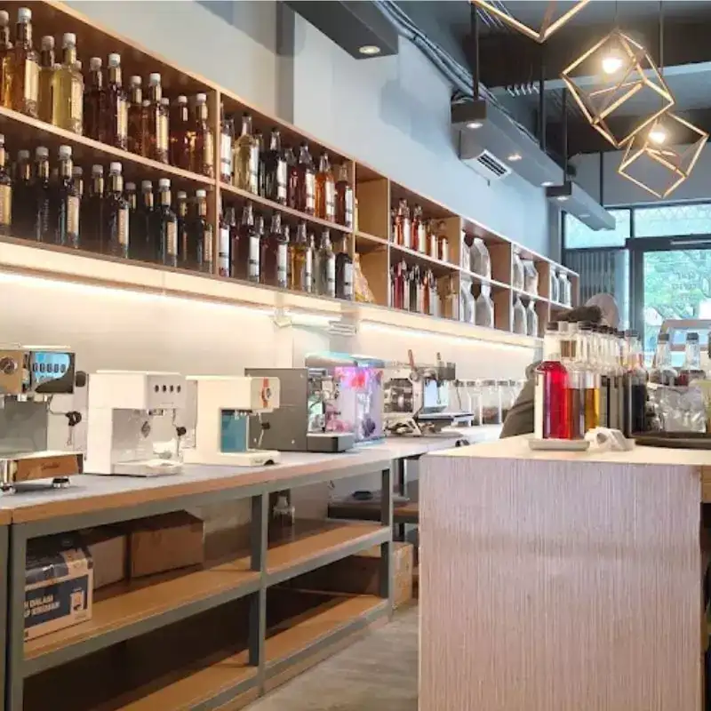 Interior toko Gemi, menunjukkan mesin espresso, syrup, dan biji kopi pilihan dari supplier biji kopi pilihan yang lengkap.
