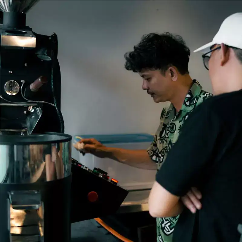 Ahli roasting Gemi sedang mengontrol mesin untuk menghasilkan biji kopi pilihan, menjamin kualitas supplier biji kopi pilihan.